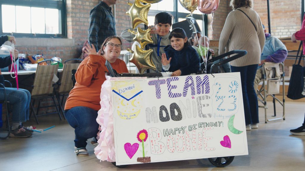 A family holding up their hand-made Buddy Walk Family Fun Day team sign