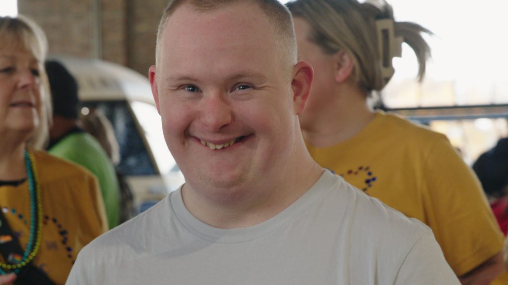 A young man smiling among friends at a DSANWI gathering