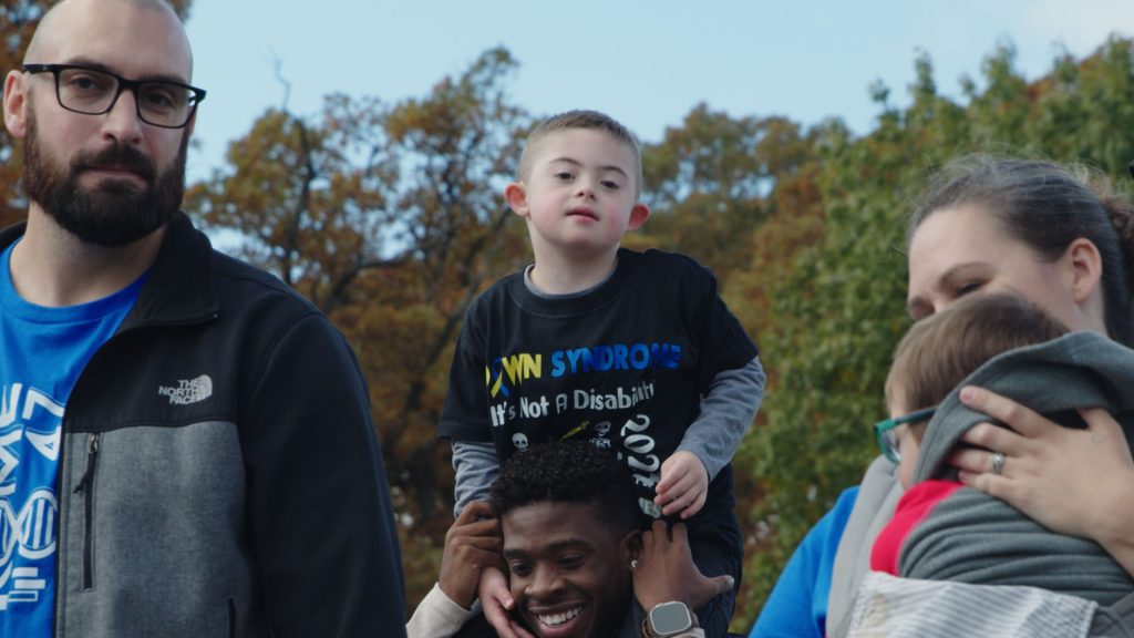 A dad carrying his son on his shoulders at the Buddy Walk Family Fun Day