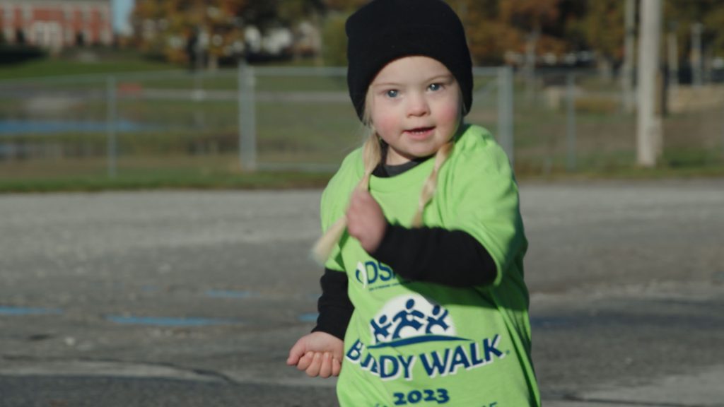 A young walker in a Buddy Walk Family Fun Day t-shirt out on the field