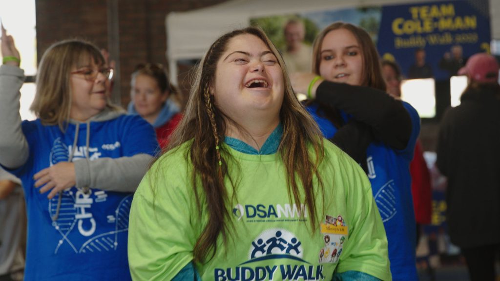 Friends in Buddy Walk Family Fun Day t-shirts laughing together at registration