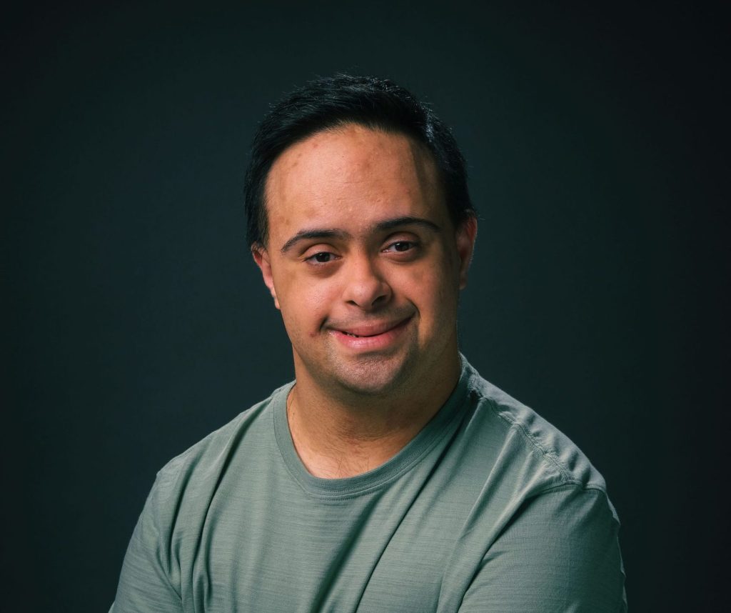 A smiling adult man with Down syndrome, studio portrait