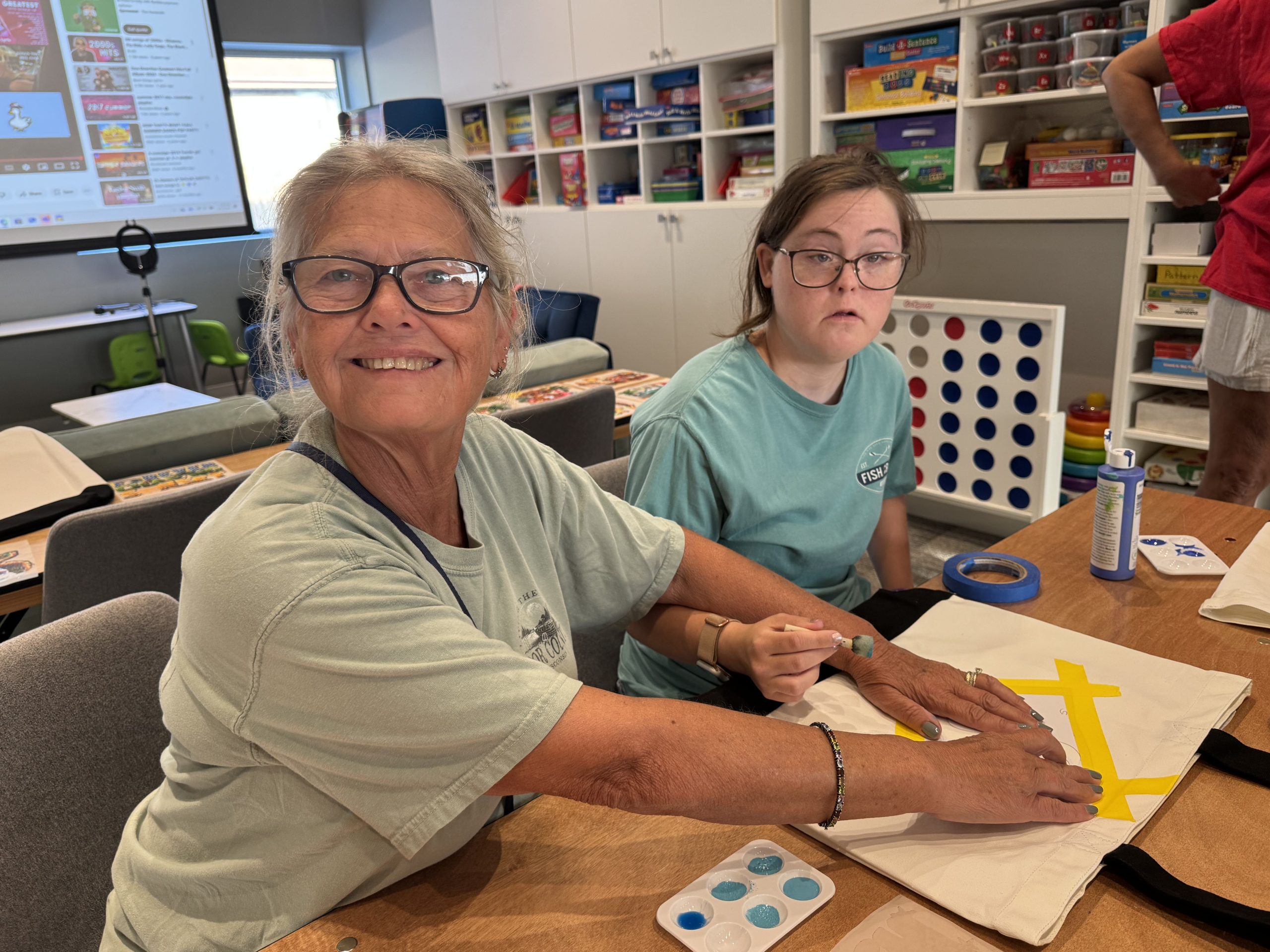 A DSANWI volunteer and a young woman working on a craft project together